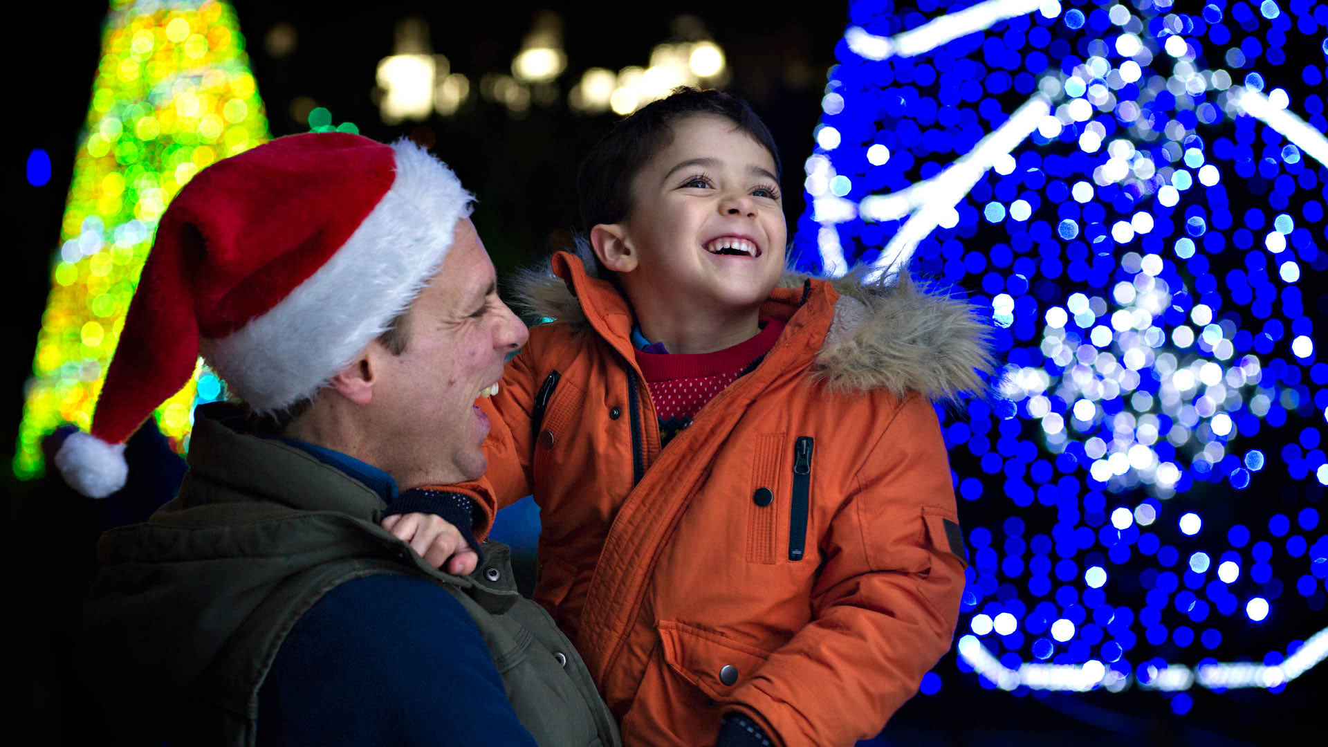 Child and man smiling at the christmas lights